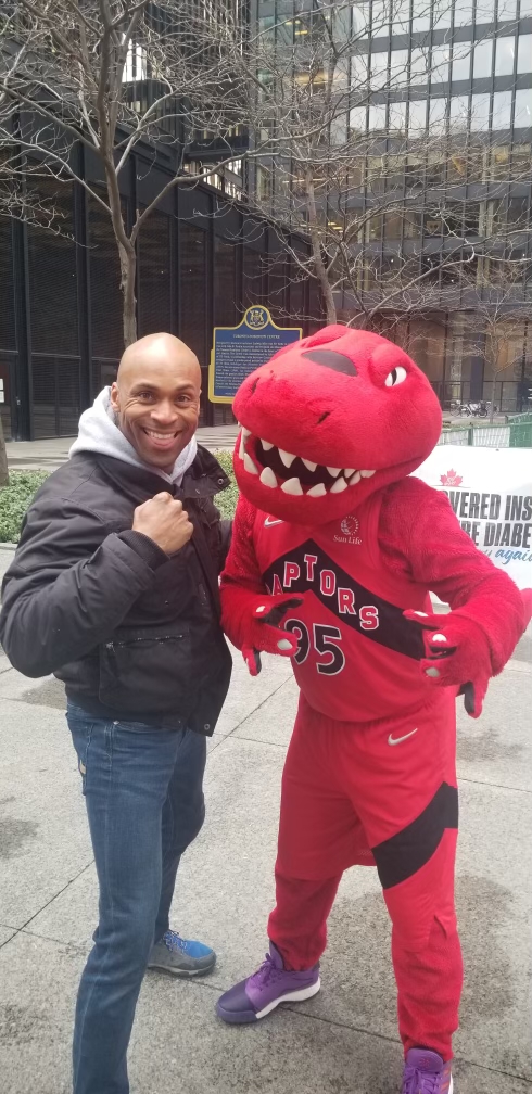Dwayne Ellis of Safety First Consulting poses with Toronto Raptor mascot.